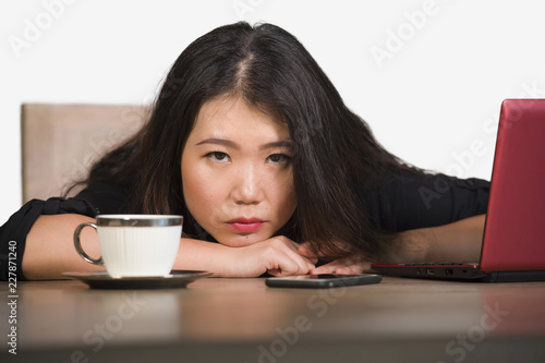 beautiful sad and depressed Asian Chinese businesswoman working in stress at office computer desk feeling overwhelmed and frustrated suffering headache and depression