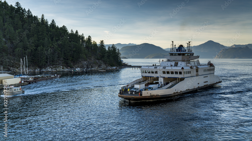 Fototapeta premium Ferry approaches the shores carrying vehicles and passengers. Beautiful British Columbia, Canada.