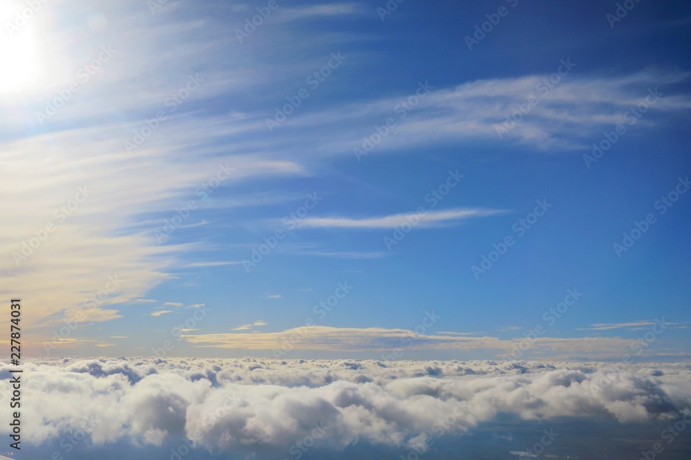 Naklejka premium Clear blue sky with white cloud in the autumn evening time. Aerial view from airplane's window. Nature background concept with copy space.