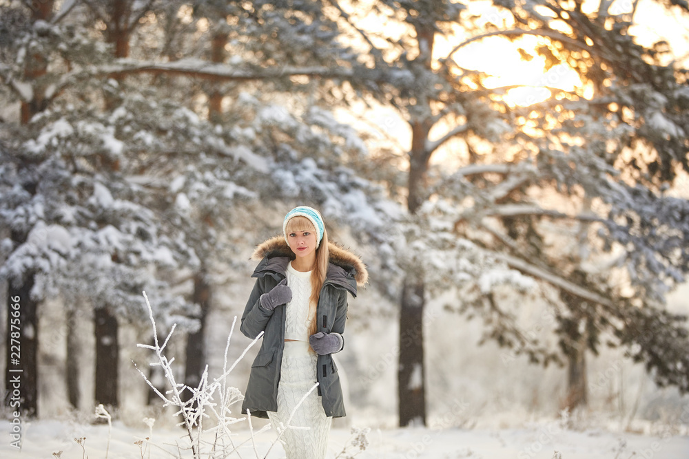 Beautiful girl with long curly hair and white clothes having fun outdoor in winter forest under snowflakes. Beautiful girl with long curly hair and white clothes having fun outdoor in winter forest under snowflakes.