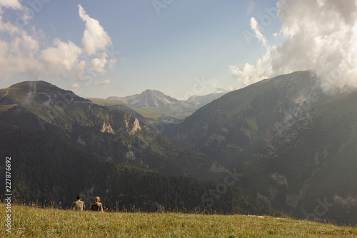 Subalpine meadow illuminate sun,tourist on rest. photo