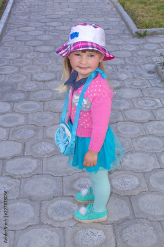 Little fashionable girl walks down the street in panama. Summer day.