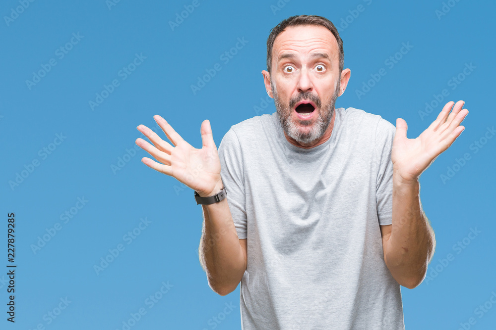 Naklejka premium Middle age senior hoary man over isolated background clueless and confused expression with arms and hands raised. Doubt concept.