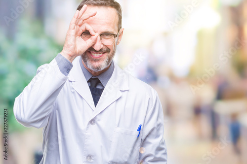 Middle age senior hoary professional man wearing white coat over isolated background doing ok gesture with hand smiling, eye looking through fingers with happy face.