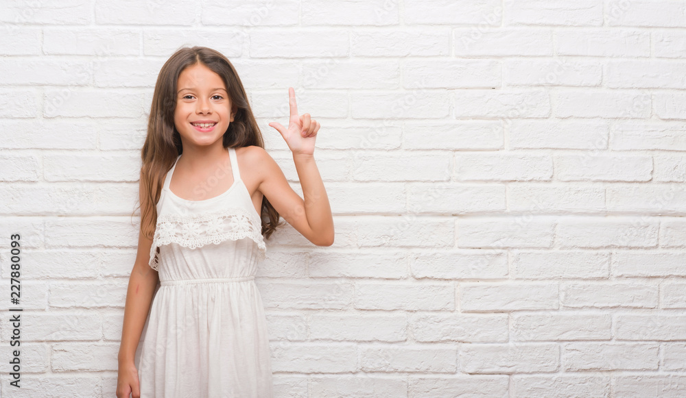 Young hispanic kid over white brick wall showing and pointing up with fingers number two while smiling confident and happy. Young hispanic kid over white brick wall showing and pointing up with fingers number two while smiling confident and happy.