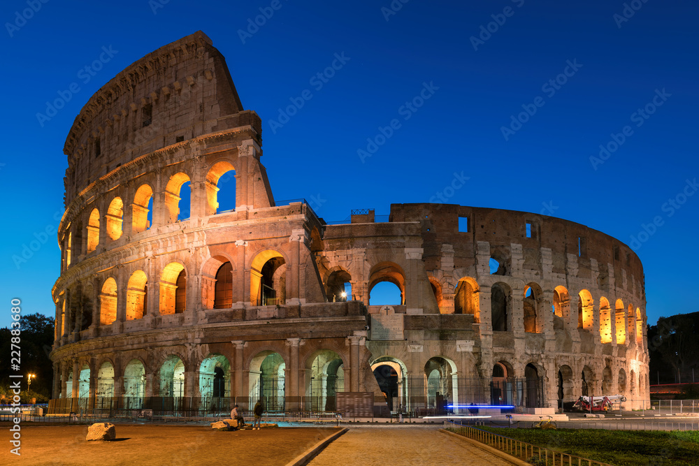 Fototapeta premium Koloseum w Rzymie, nocne oświetlenie z błękitnym niebem, Rzym, Włochy,