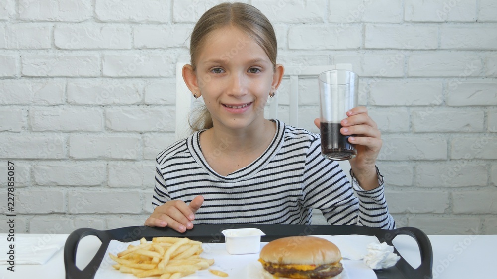 Child Eating Hamburger in Restaurant, Kid and Fast Food, Girl Drinking Juice Child Eating Hamburger in Restaurant, Kid and Fast Food, Girl Drinking Juice