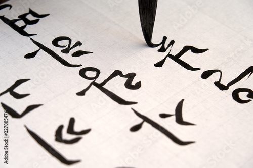 Foto The hand of a person who writes brush strokes on paper