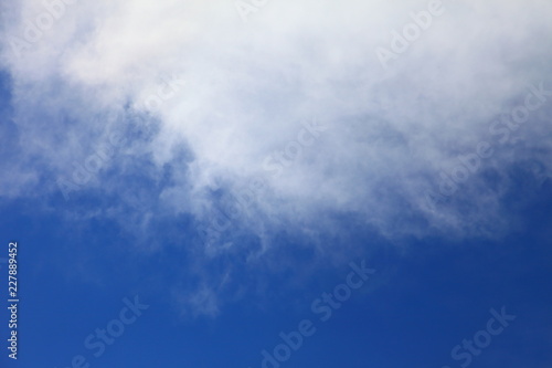 Bright blue sky with white fluffy beautiful crescent cloud formation on sunny day for design background and wallpaper