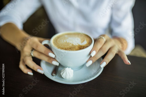 close up hand of woman holding a cup of hot latte in the cafe