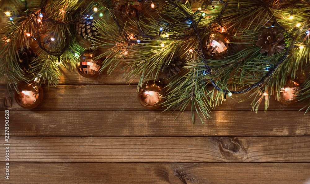 Christmas or New Year composition with pine branches, a garland and golden balls on a wooden plank background with copy space. Christmas or New Year composition with pine branches, a garland and golden balls on a wooden plank background with copy space.