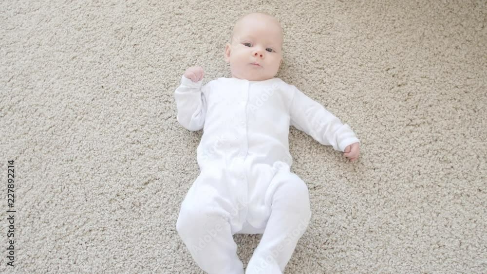 Cute funny baby lying on a beige carpet