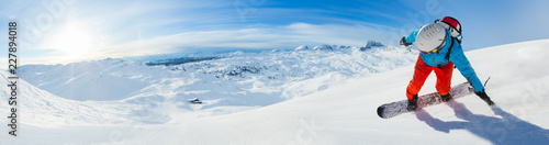 Snowboarder skiing downhill, panoramic format
