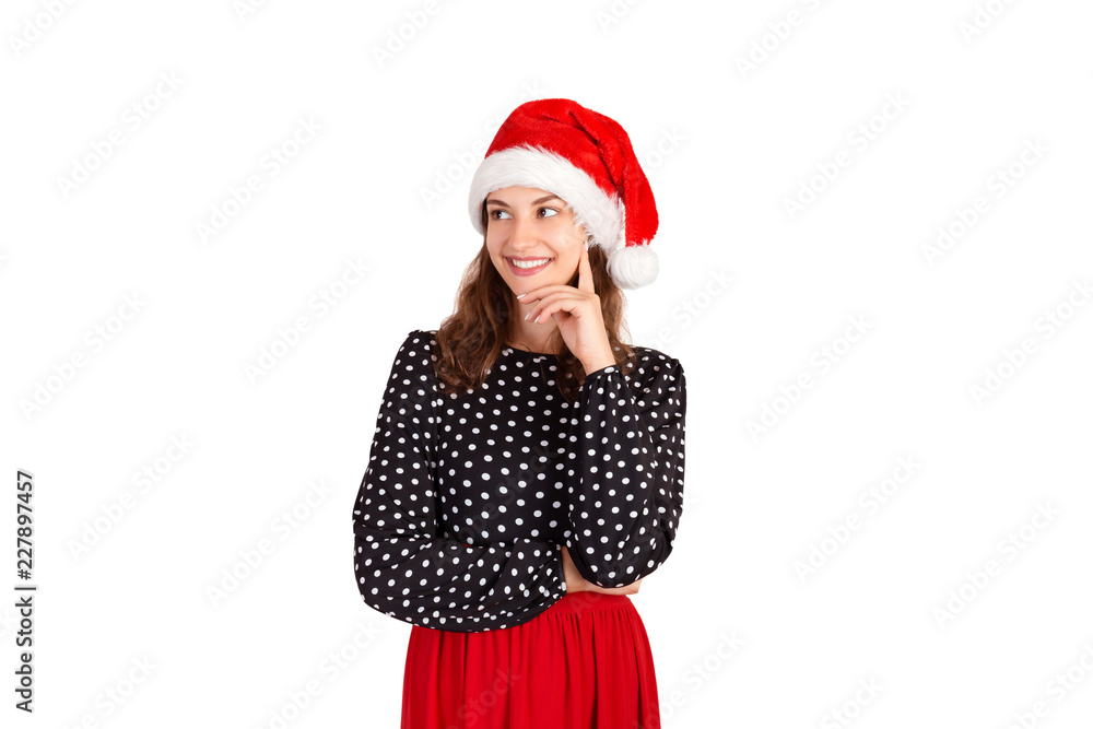 Confident attractive european woman standing with smiling broadly and glancing at left. emotional girl in santa claus christmas hat isolated on white background. holiday concept Confident attractive european woman standing with smiling broadly and glancing at left. emotional girl in santa claus christmas hat isolated on white background. holiday concept