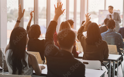 Raised up hands and arms of large group in seminar class room to agree with speaker at conference seminar meeting room photo