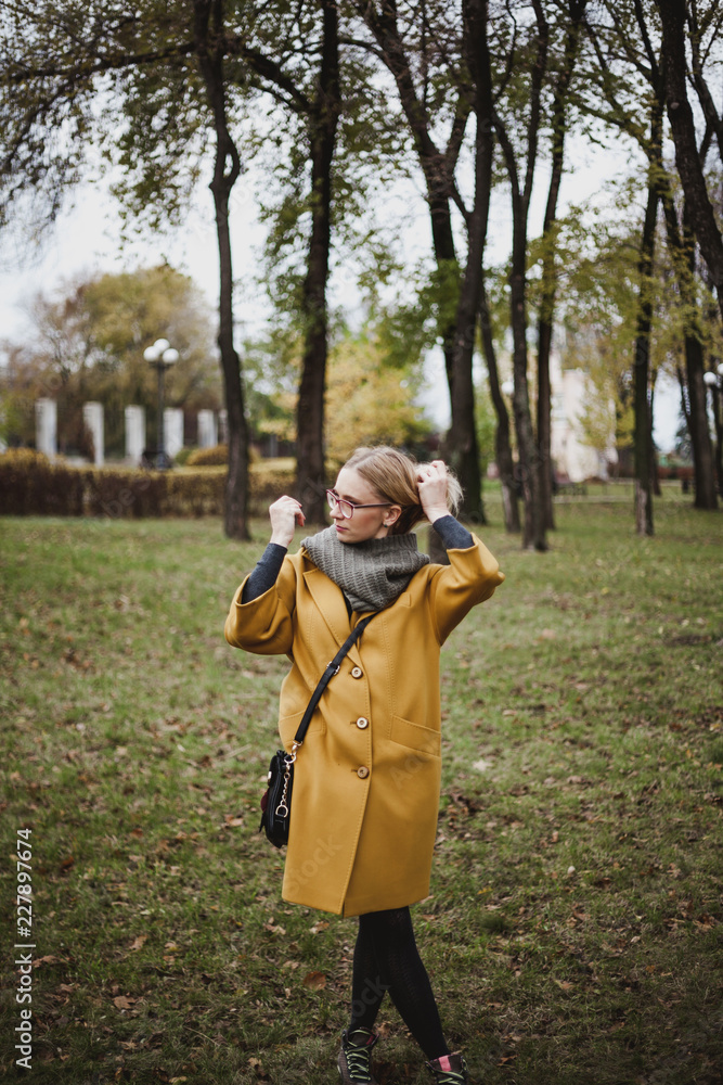 Naklejka premium Cute blonde is walking in autumn park