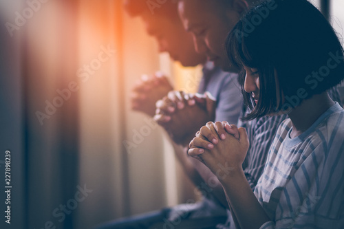 Asian Christian groups sitting within the Church Catholic. They clasped hands and closed his eyes and prayed for blessings from God. A pale sun shone in a place of worship. Everyone smiled happily.