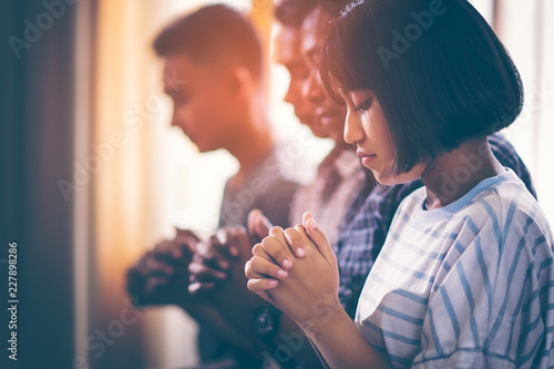 Asian Christian groups sitting within the Church Catholic. They clasped hands and closed his eyes and prayed for blessings from God. A pale sun shone in a place of worship with copy space.