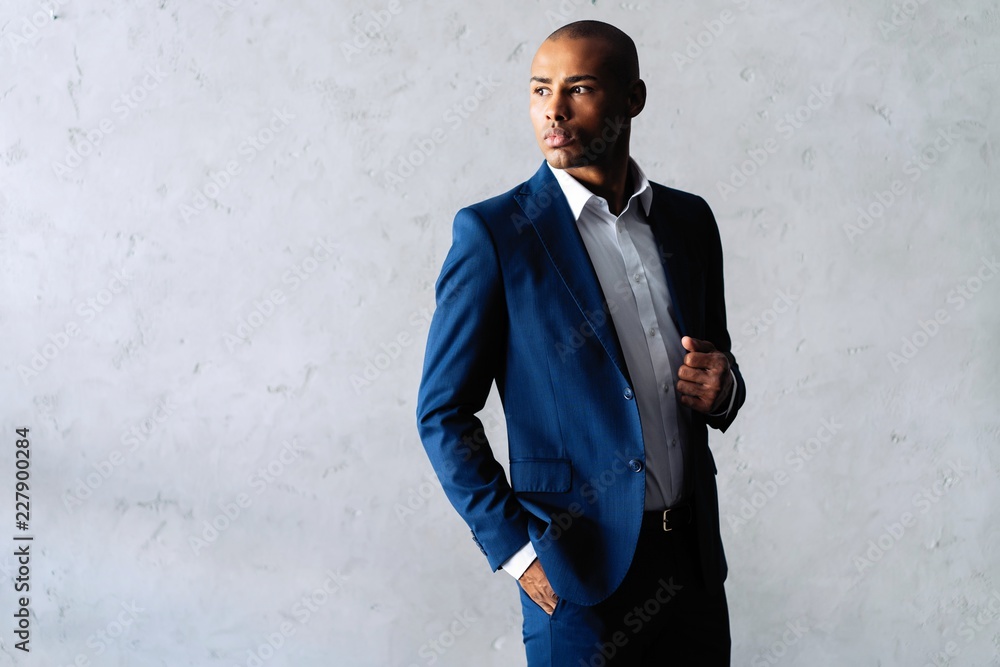Cool african businessman standing on grey background. Cool african businessman standing on grey background.