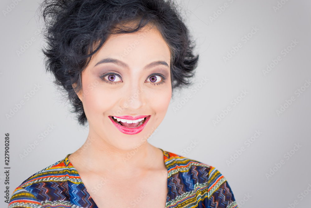 Close-up of the faces of beautiful young Asian women. She opens her mouth,  smiling and showing emotions, glad and surprised. Wearing a colourful  t-shirt Short curly hair, isolated on white background. Stock