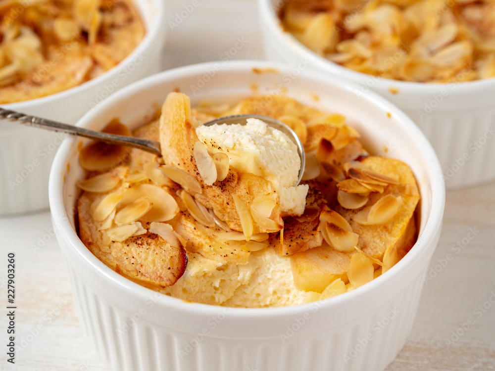 Cheesecake on white wooden table in kitchen. Delicate curd dessert with apples, almond flakes and cinnamon, side view Cheesecake on white wooden table in kitchen. Delicate curd dessert with apples, almond flakes and cinnamon, side view
