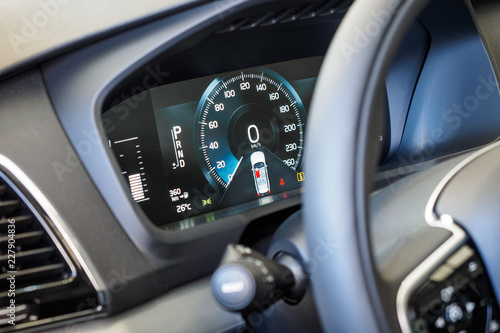 Luxury car interior details. Dashboard and steering wheel. Modern car illuminated dashboard close-up. Speedometer. Speed control. Digital screen of telling speed of the car. © Evgeniy