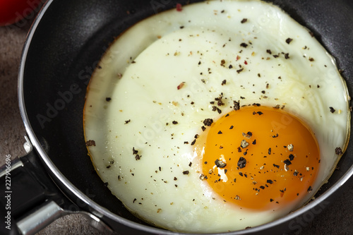 One fried egg with ground pepper in a little pan