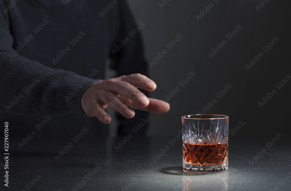 Man's hand reaches for a glass of alcohol. Man's hand reaches for a glass of alcohol.