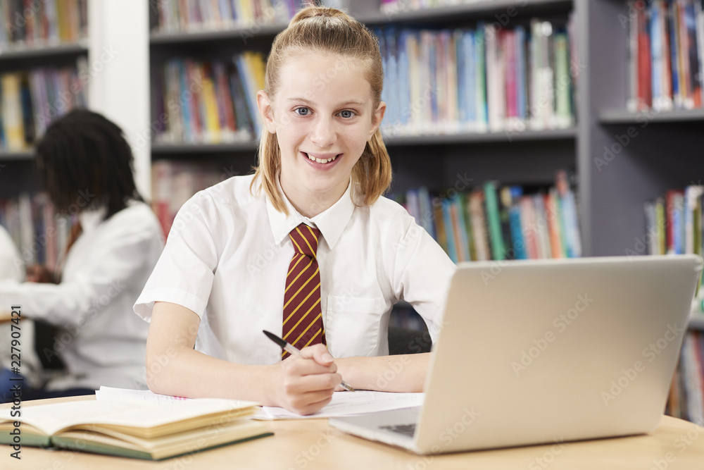 Portrait Of Female High School Student Wearing Uniform Working At Laptop In Library Portrait Of Female High School Student Wearing Uniform Working At Laptop In Library