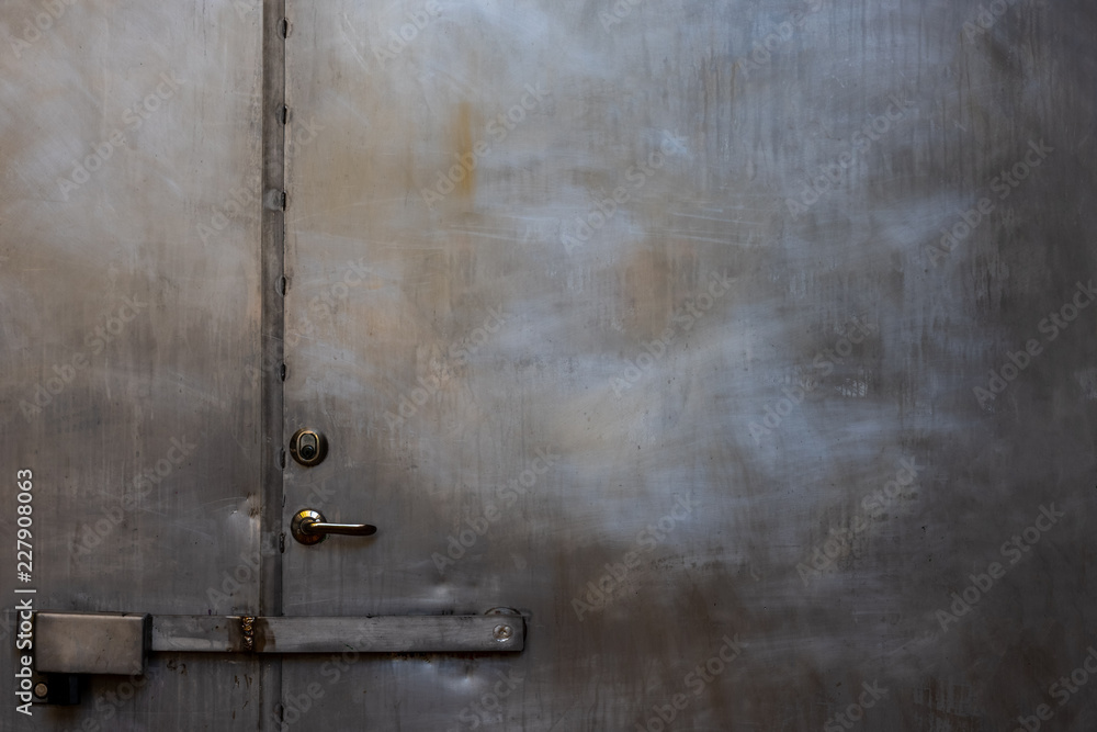Closeup of closed scratched grungy shiny steel door with locks and handle. Closeup of closed scratched grungy shiny steel door with locks and handle.