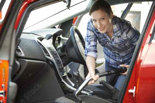 Portrait Of Woman Cleaning Interior Of Car Using Vacuum Cleaner