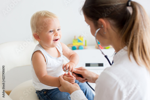 Pediatrician examining baby boy. Doctor using stethoscope to listen to kid