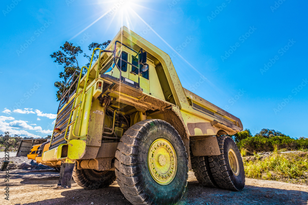 Enormous green dumper truck under sun flare Enormous green dumper truck under sun flare