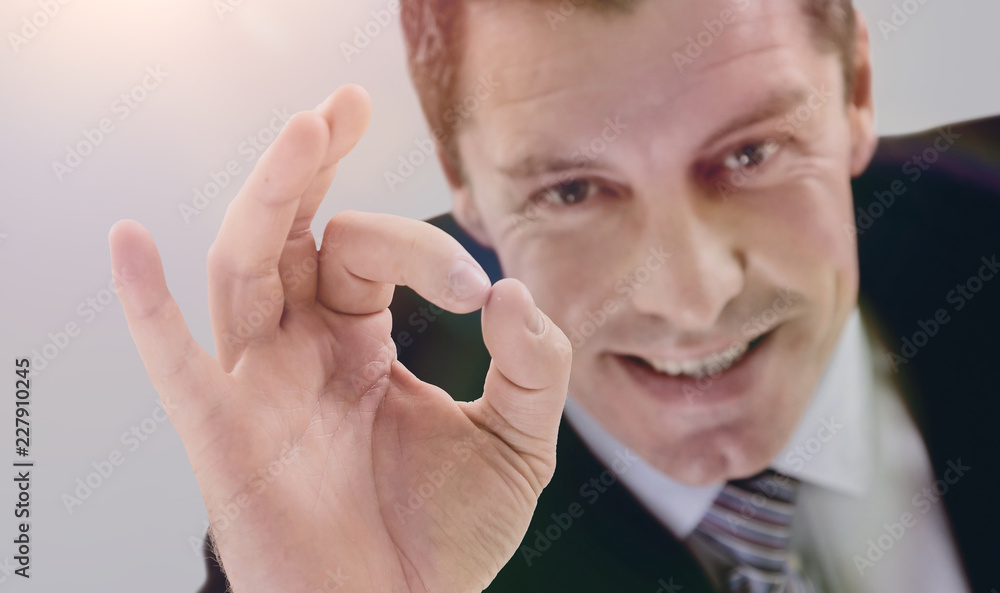 Fototapeta premium Happy young man in suit gesturing OK sign and smiling.