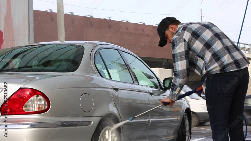 Man washing his car with water spray from high pressure washer. Car wash self-service. Man washing his car with water spray from high pressure washer. Car wash self-service.
