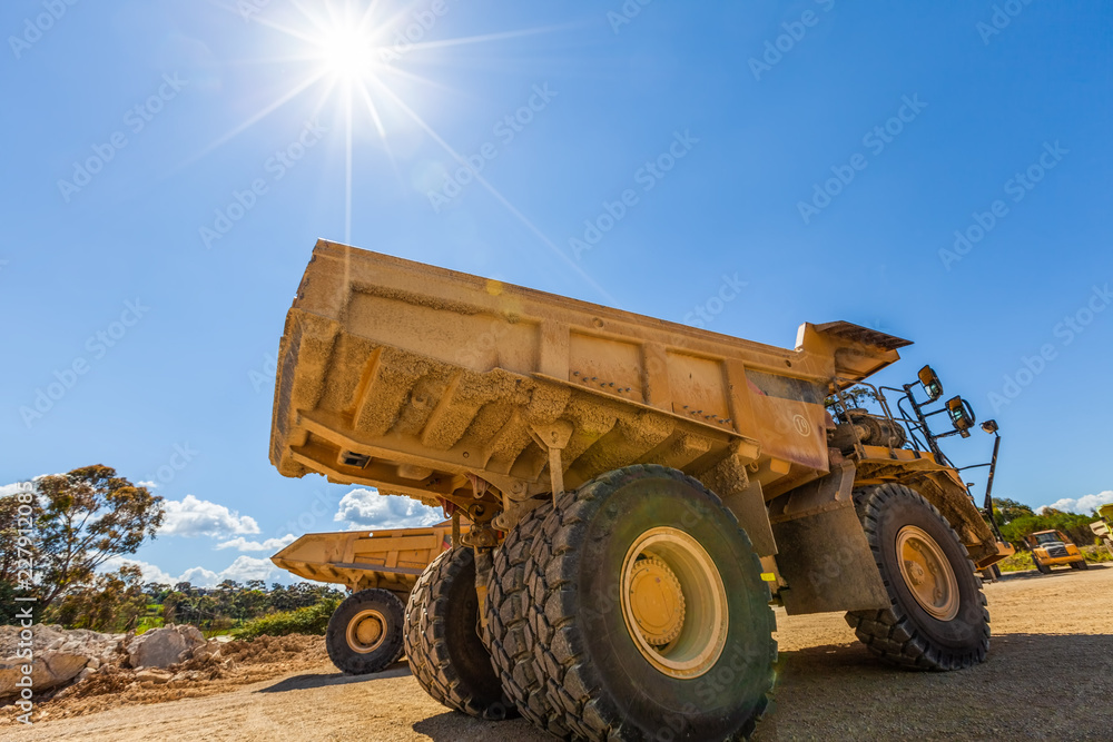 Sun shining on large yellow dumper trucks Sun shining on large yellow dumper trucks