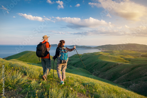 Young couple hike in the mountains. A man and a woman walking and looking at the beautiful landscape.