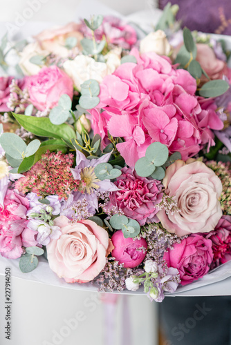 beautiful spring bouquet. Young girl holding a flowers arrangement with various of colors. white wall.