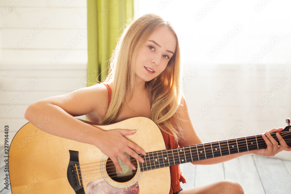 Girl playing guitar and singing. Young woman with long hair studying music  at home. Woman sitting on floor and plays acoustic guitar and sing alone at  home Stock Photo | Adobe Stock