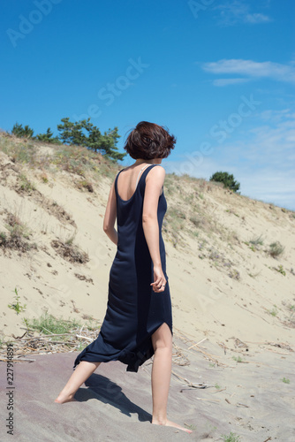 Young brunette woman in dress walking along the seashore © ottochka