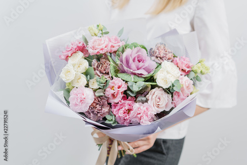 Fototapeta Naklejka Na Ścianę i Meble -  beautiful spring bouquet. Young girl holding a flowers arrangements with various of colors. white wall.