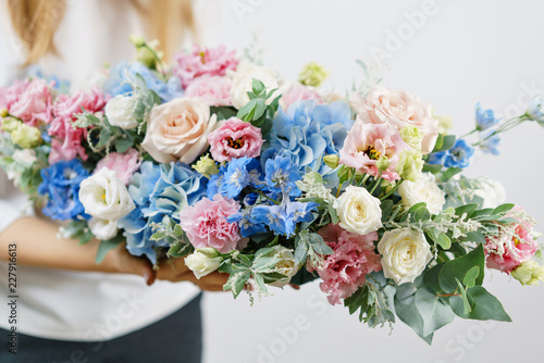 beautiful spring bouquet. Young girl holding a flowers arrangement with various of colors. white wall.