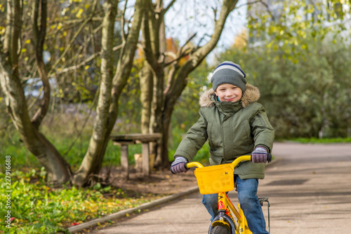 boy in a green jacket rides a yellow bike