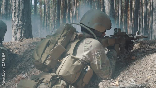 Soldiers are fighting in a trench in a smoky forest photo