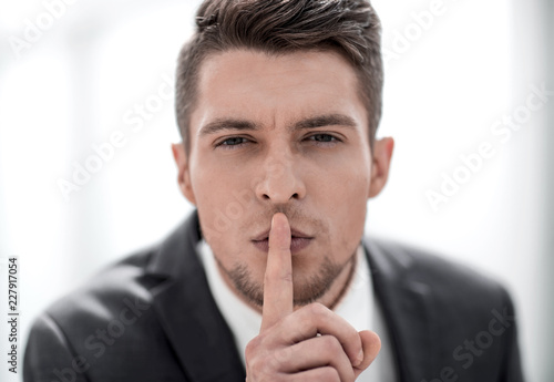 Face businessman with finger on lips