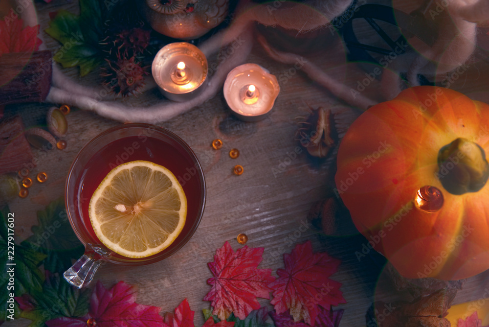 Autumn hot tea with lemon and spices in glass cup.on rustic table with leaves and pumpkins. Autumn Halloween style. Autumn hot tea with lemon and spices in glass cup.on rustic table with leaves and pumpkins. Autumn Halloween style.