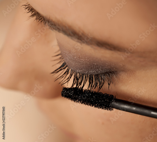 Closeup of young woman applying mascara