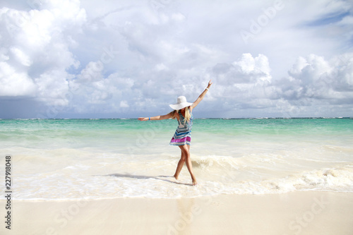 Young slim beautiful woman dancing  on the beach, playful, dancing, running, summer dream vacation, sunny, having fun, positive mood,  splashing water, happy 