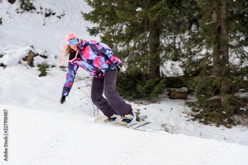 Beautiful young woman snowboarding on the snowy ski slopes on a winter day in the Alps in the Brandnertal, Vorarlberg Austria