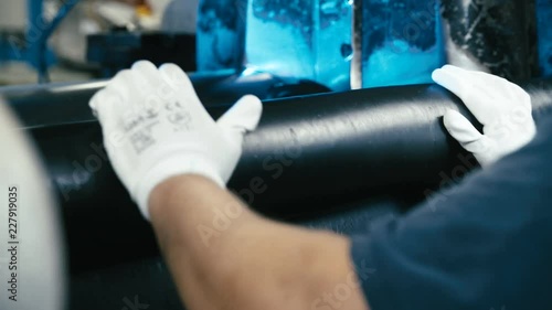 Person rolling together rubber sheet close-up 4K. Long shot of industrial process rolling the rubber sheet in focus from machine cylinders. photo